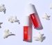 Bright lip glosses and flowers on white background, flat lay